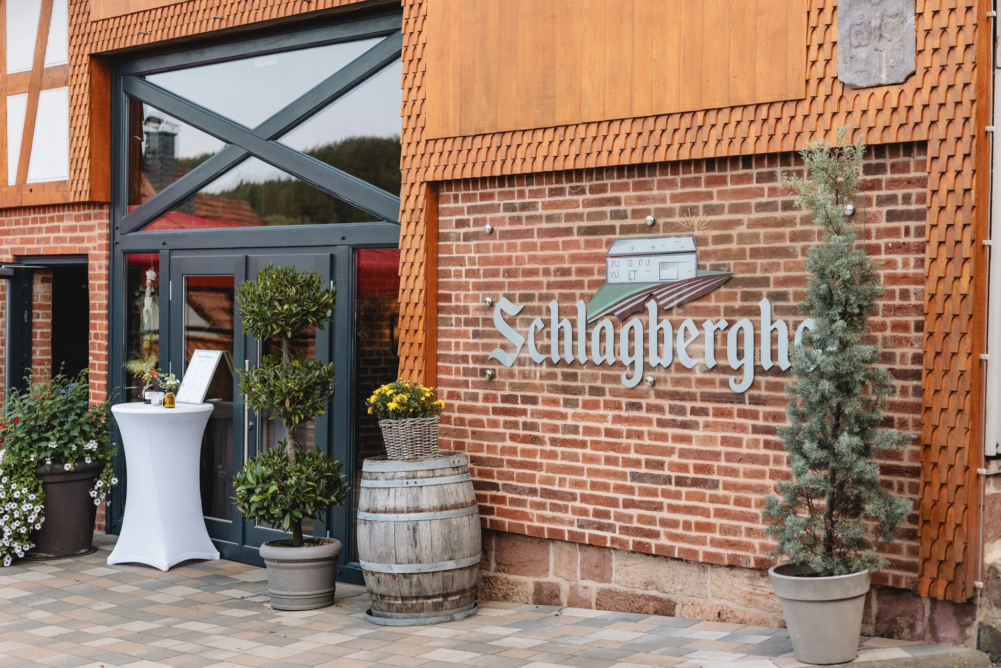 Haupteingang des Schlagberghofs in Kleinlüder mit einem Stehtisch und einem Weinfass als Dekoration.