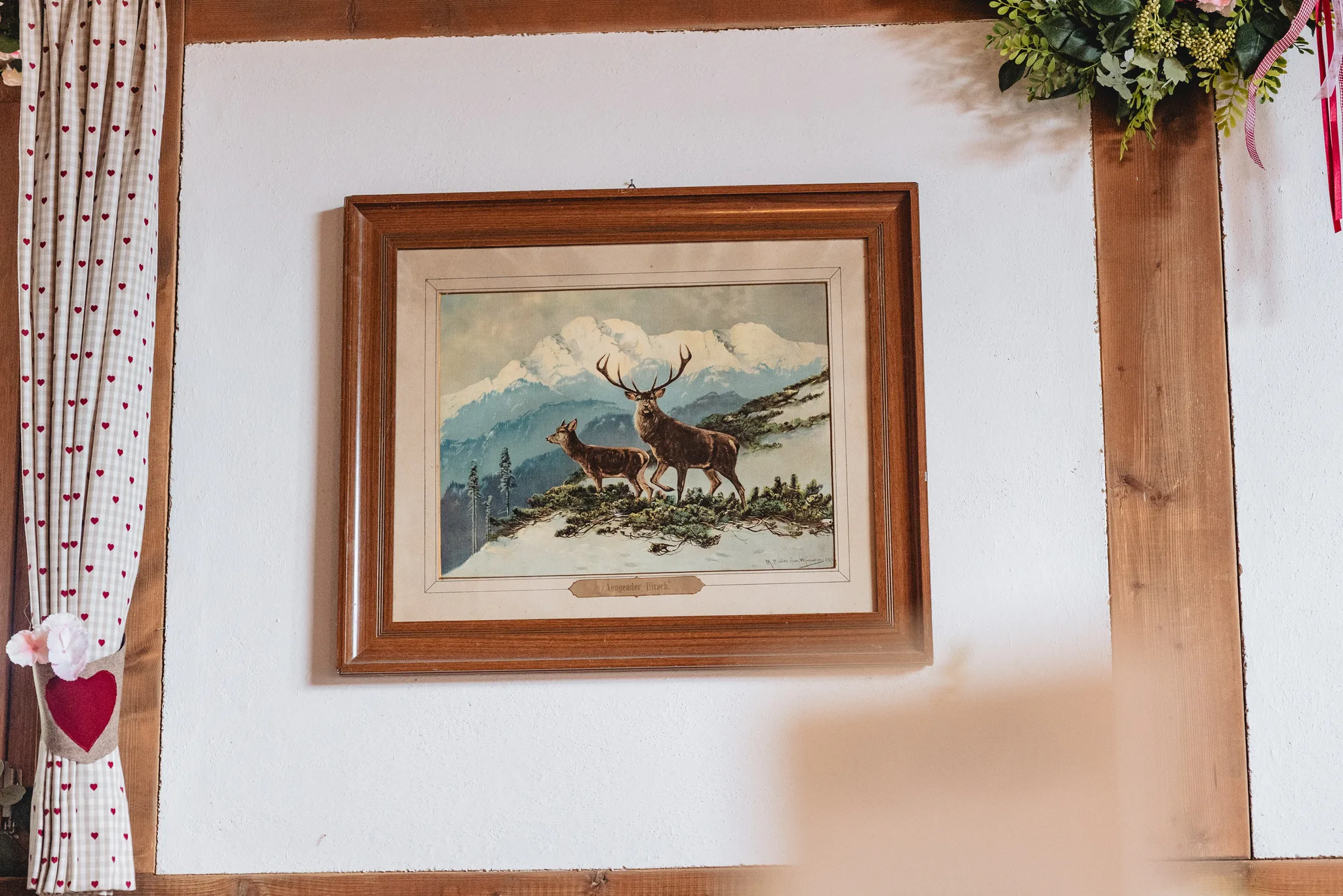Ein gerahmtes Bild mit einem Hirsch-Motiv hängt an einer weißen Wand in einem rustikalen Raum in Kleinlüder.