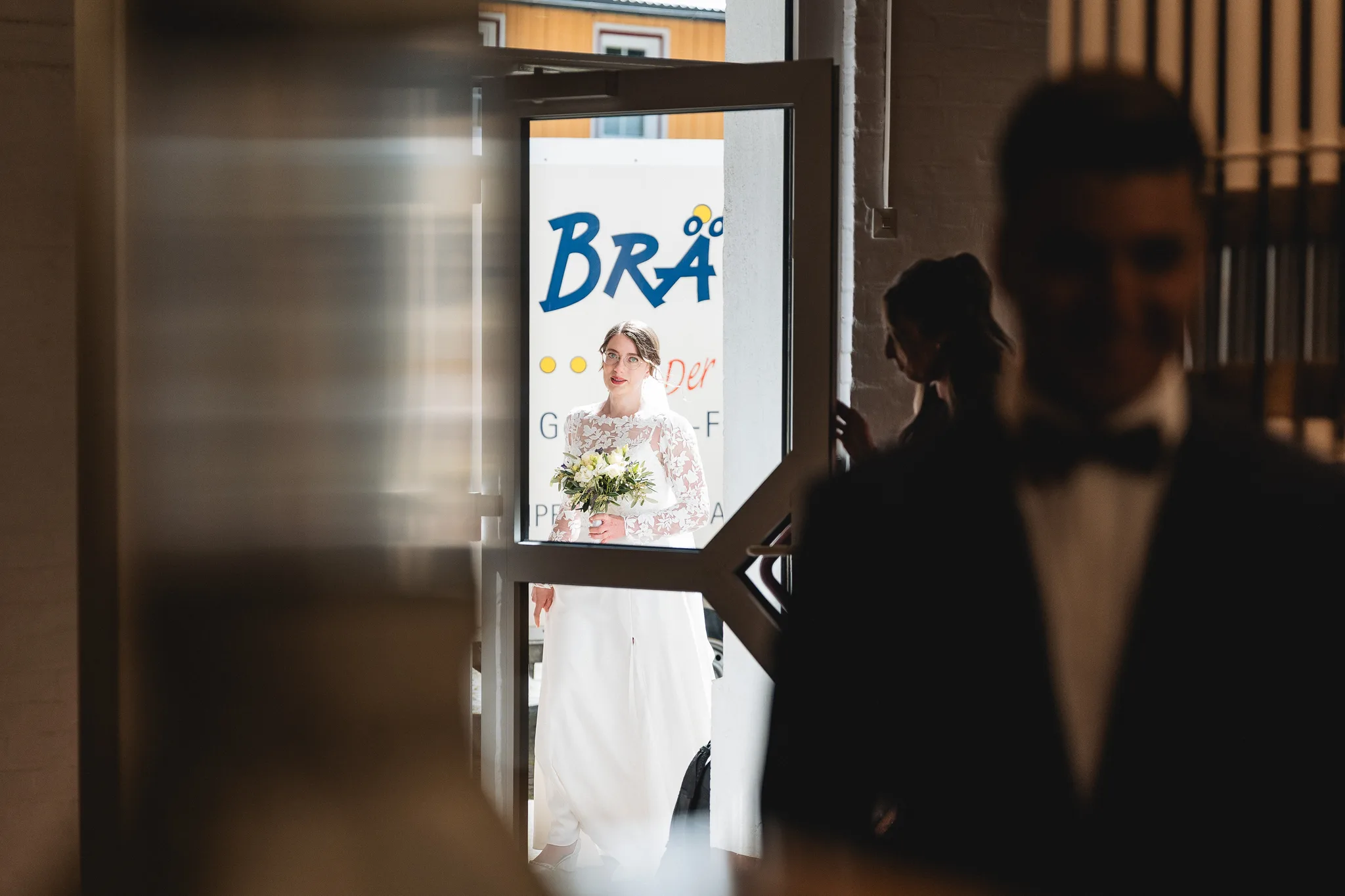 Stefanie kommt an ihrem Hochzeitstag durch die Tür der Mühle, während Ralf ihr erwartungsvoll entgegenblickt.